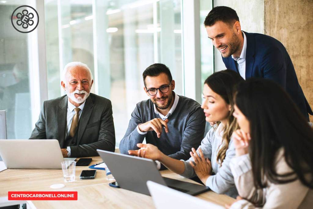 Un grupo de profesionales discutiendo en una reunión, con laptops y documentos sobre la mesa.