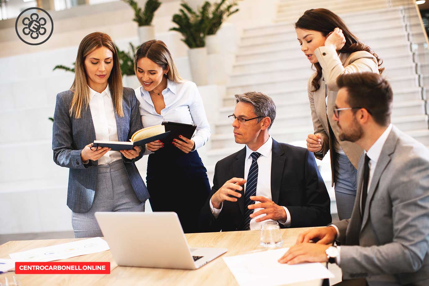 Grupo de profesionales discutiendo y revisando documentos en una oficina moderna, con un ambiente colaborativo y formal.