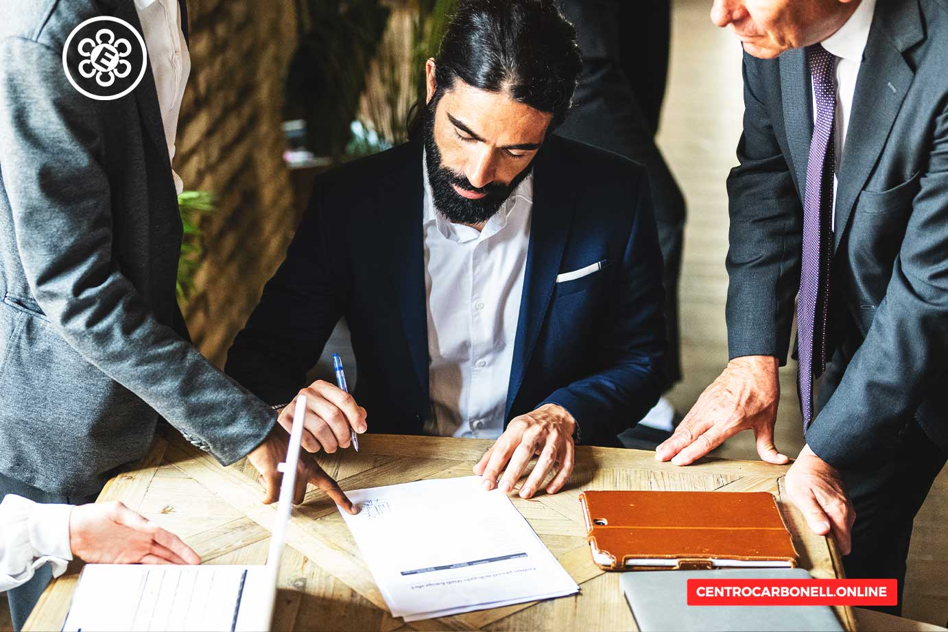 Un grupo de personas discutiendo y firmando un contrato en una mesa de trabajo.