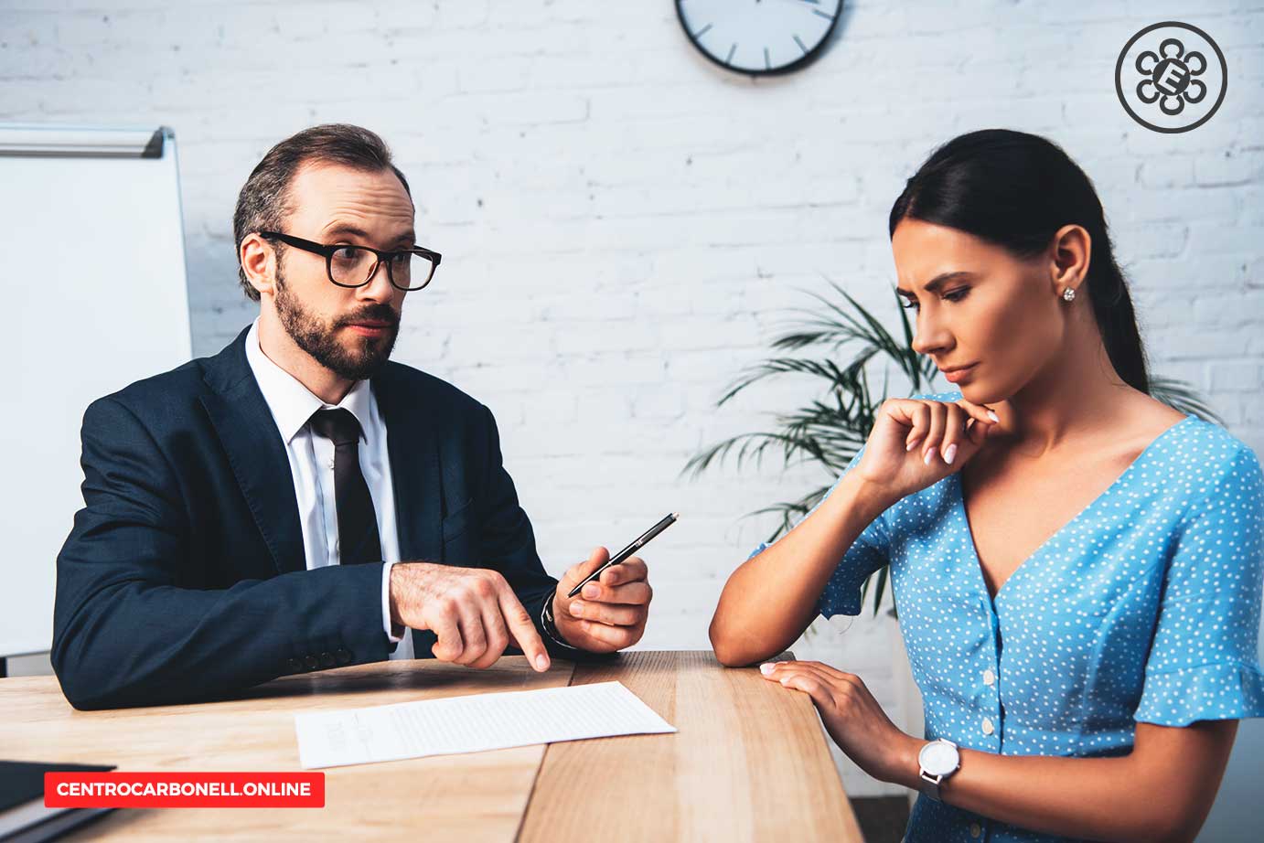 Un abogado discutiendo un documento con una mujer en un entorno de oficina, mientras ella escucha atentamente.