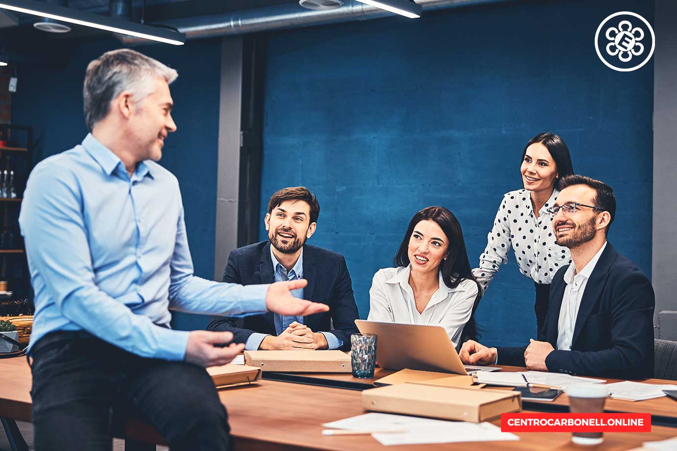 Reunión de un grupo de profesionales en una oficina moderna, discutiendo estrategias legales, con una computadora portátil y documentos sobre la mesa.