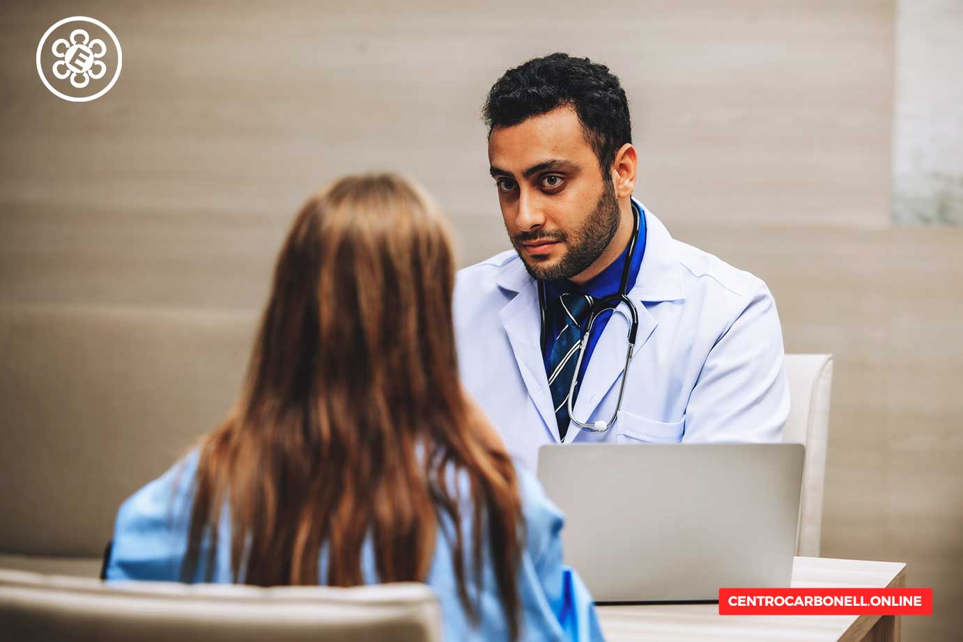 Un médico en un consultorio habla con una paciente, quien está sentada frente a él. La conversación parece centrarse en la atención médica y el consentimiento informado.