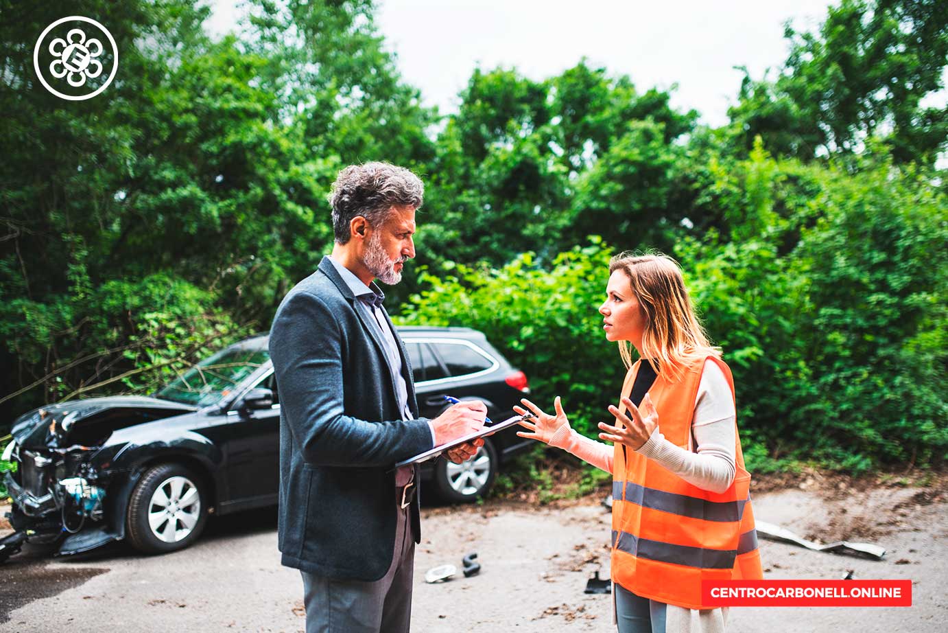 Dos personas discutiendo en el lugar de un accidente de tráfico, con un coche dañado al fondo.