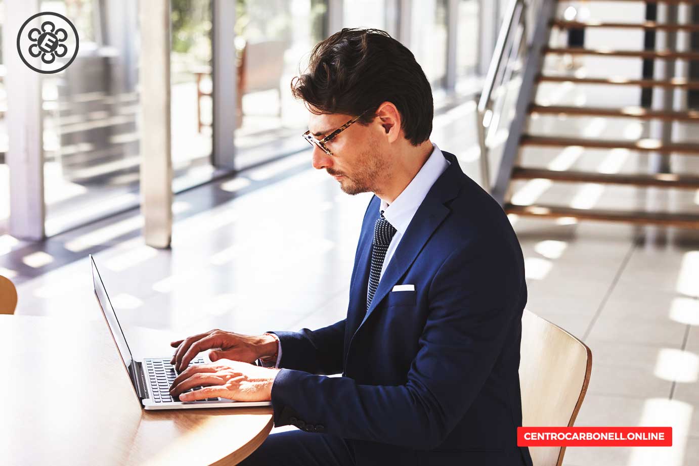 Hombre de negocios trabajando en una computadora portátil en un entorno moderno y luminoso, vistiendo un traje formal.