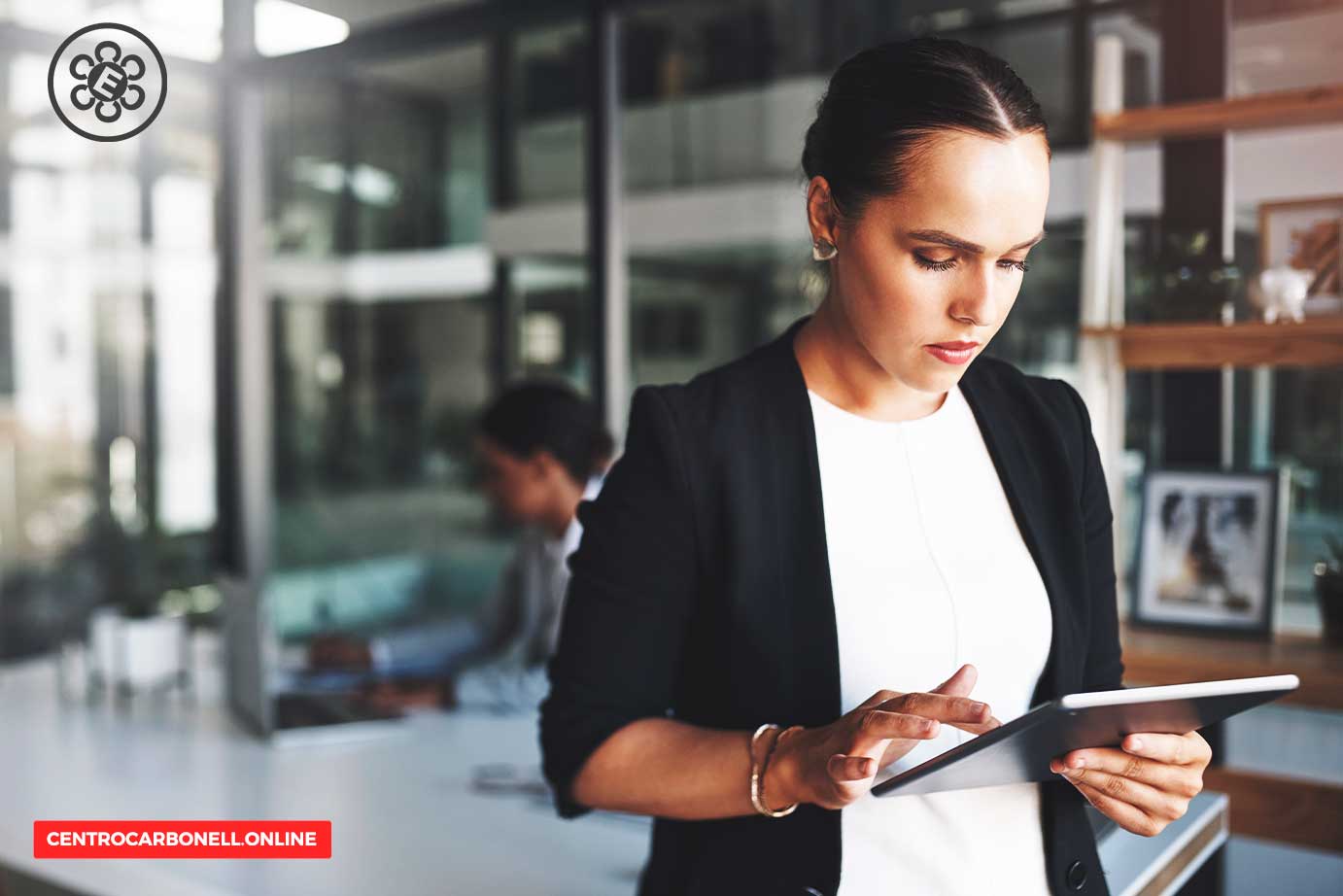 Mujer de negocios utilizando una tableta en un ambiente de oficina moderna.