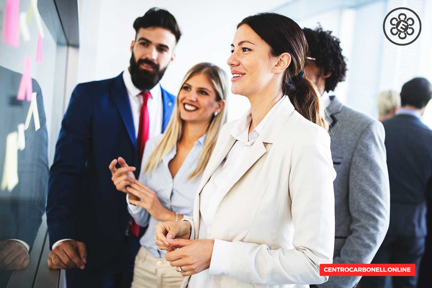 Grupo de profesionales en una reunión de trabajo, viendo una presentación en un pizarrón.