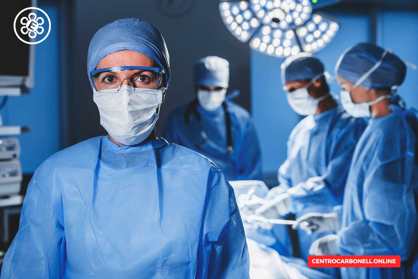 Médico cirujano en un quirófano, con máscara y gafas, rodeado de otros profesionales de la salud que realizan una operación.