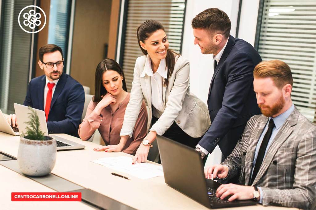 Grupo de profesionales en una reunión, discutiendo ideas sobre un proyecto, con laptops en la mesa.