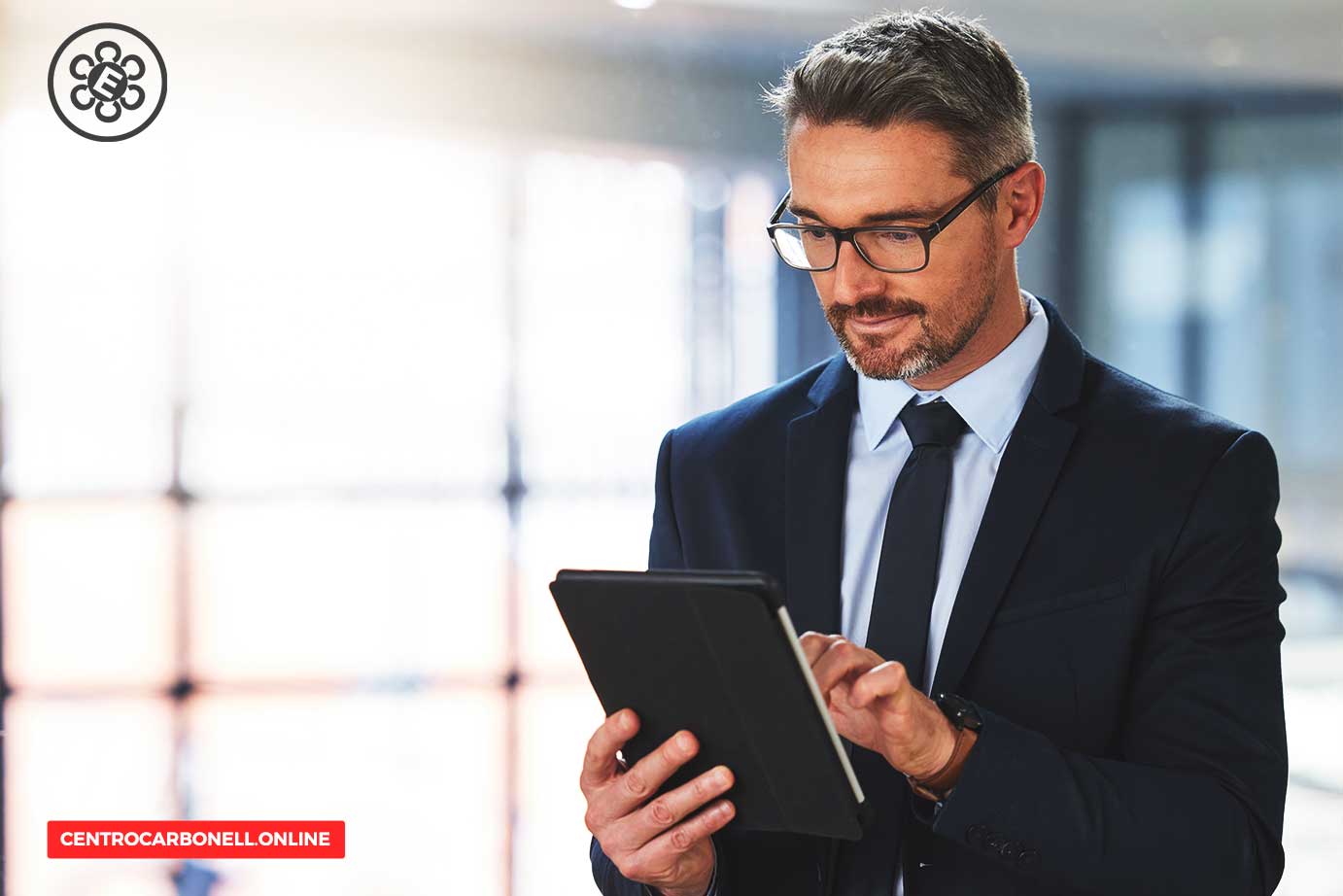 Hombre de negocios con gafas, usando una tableta en un entorno moderno y luminoso.