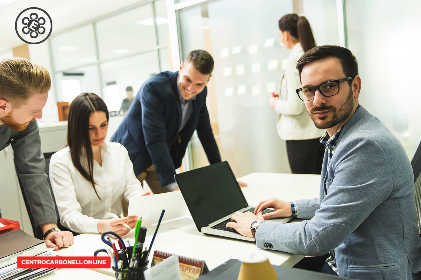 Grupo de profesionales en una oficina colaborando en un proyecto frente a una computadora portátil.
