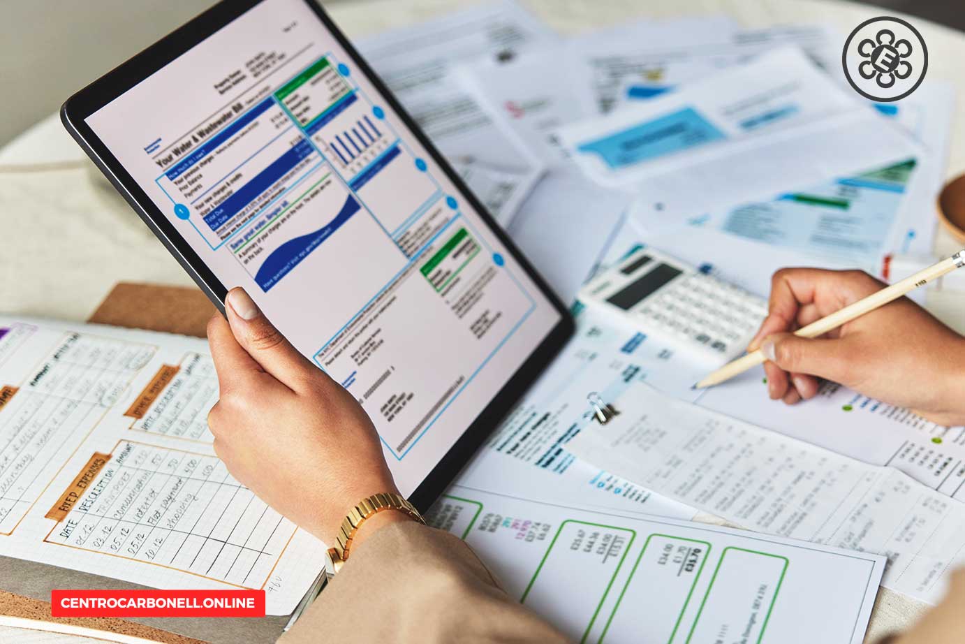 Una persona revisando datos financieros en una tablet, con documentos y gráficos esparcidos sobre una mesa.