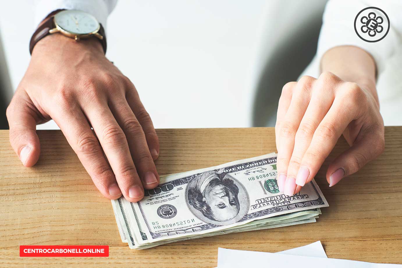 Una mano masculina y una mano femenina colocando billetes de dólar sobre una mesa de madera.